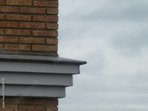 vertical brown wall of a building with gray border and cloudy sky background