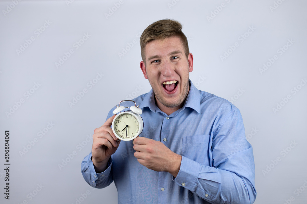 Business young man wearing a casual shirt over white background holding a clock Business young man wearing a casual shirt over white background holding a clock