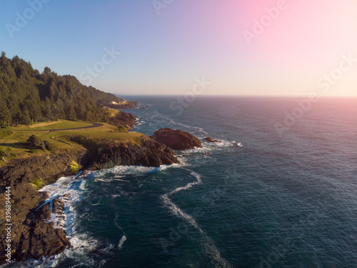 Aerial drone panoramic view of rocks in the ocean. Rocky coast with green plants. Ocean waves. Amazing natural landscape. view from above.