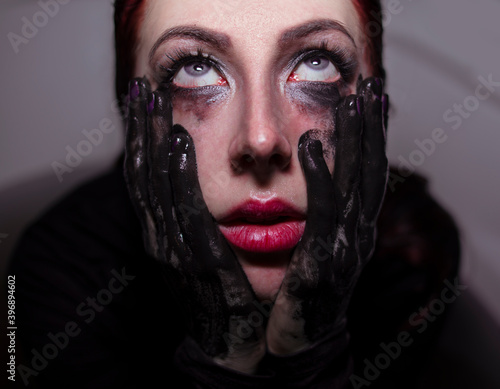 
Girl with red hair and black handprints on her face 