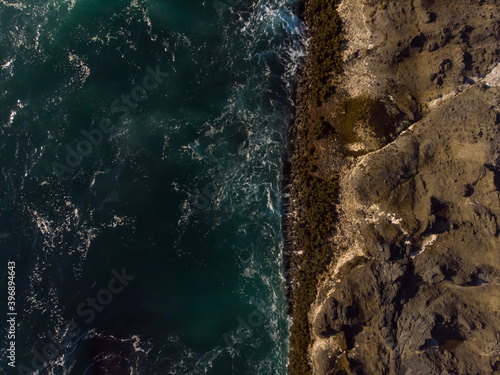 Aerial top view of ocean waves and fantastic rocky coast. Wallpaper design. Amazing landscape. View from above.