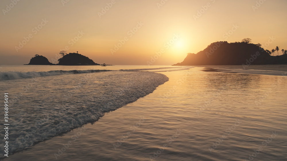 Fototapeta premium Sunset aerial at ocean waves. Sun silhouette of paradise mountain island at wavy sea bay. Crashing water. Tropic nature seascape at El Nido islet, Philippines, Asia at aerial view