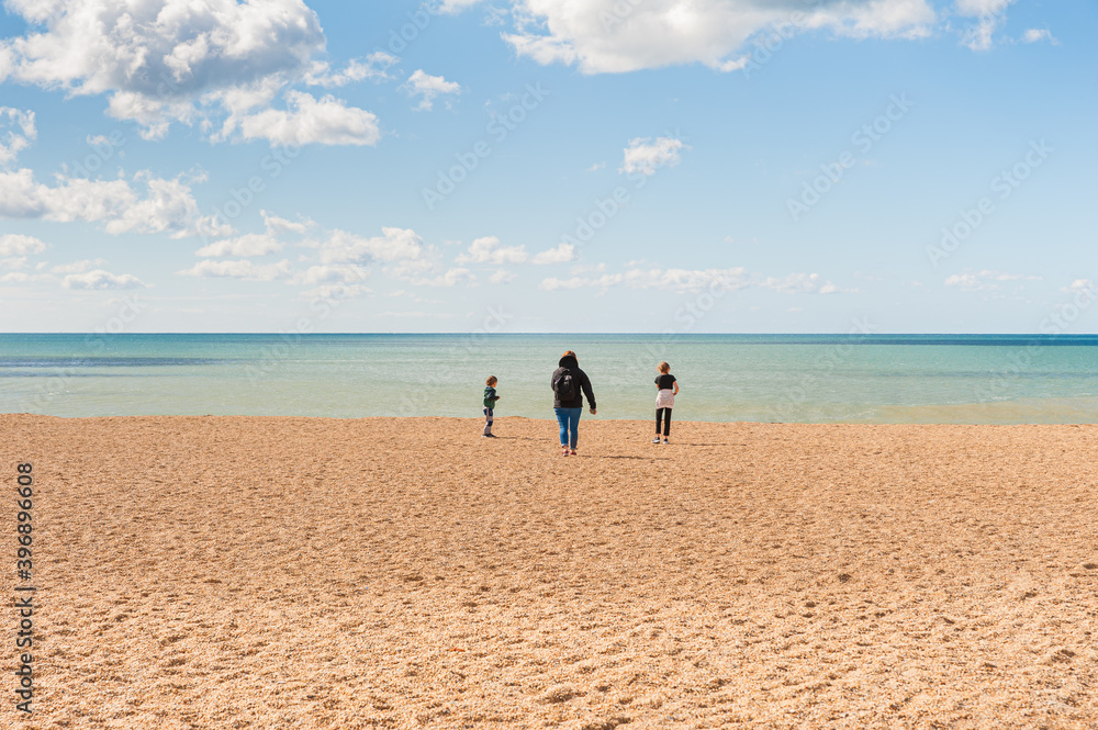 Obraz premium Family day out at the beach during sunny but windy day. Children roaming wildly and enjoying their trip. Jurassic Cliffs Coast and golden beach in West Bay.