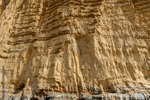 The imposing and eroded sandstone cliffs exposing millions of years of sedimentary geological layers. West Bay in Dorset on the Jurassic coast.