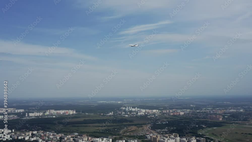 Aerial shot from drone on the airplane flying across the sky over city and approaching for landing Aerial shot from drone on the airplane flying across the sky over city and approaching for landing