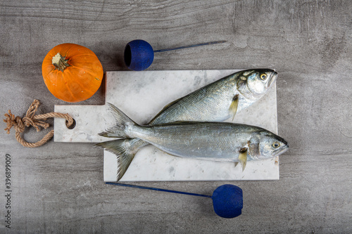 Raw Bluefish. (Latin; Pomatomus Saltatrix). Fresh fish with the vegetables, condiment and lemon, bluefish. Food preparation. photo