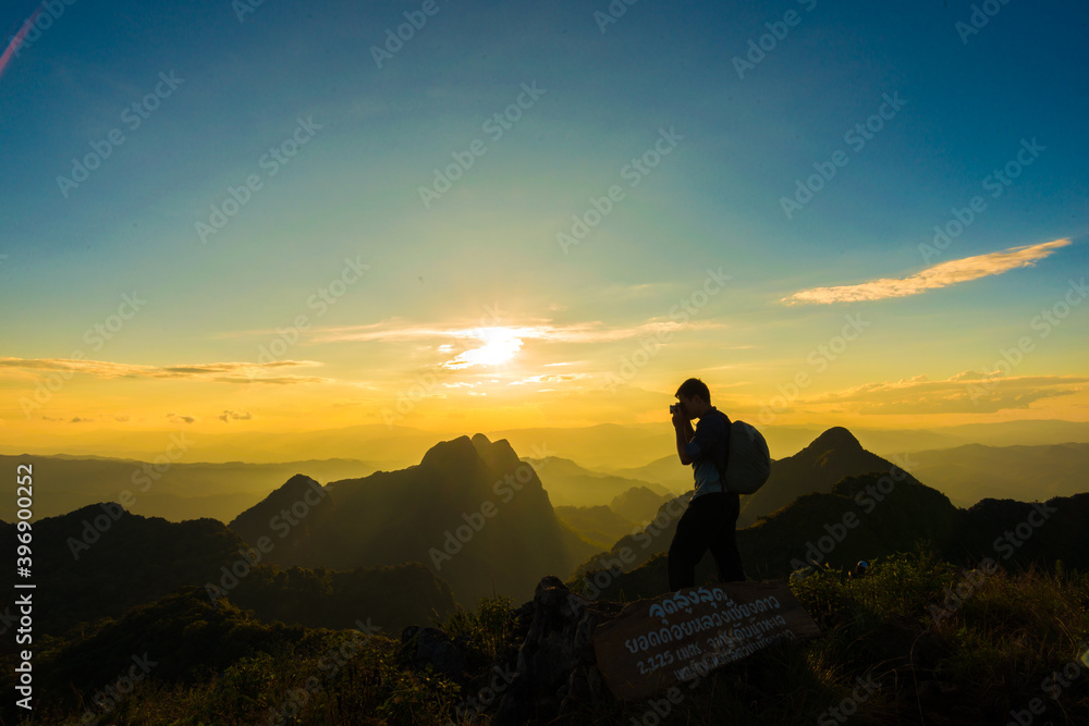 Trekking man take photo of dramatic sunset on top of mountain