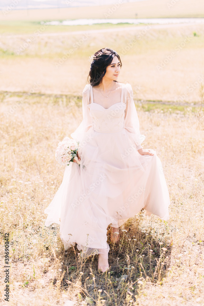 The bride walks in a powdery dress with a wedding bouquet in her hands on the background of nature