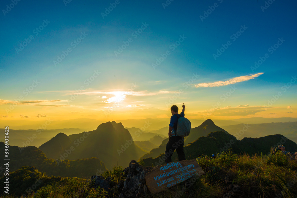 Trekking man take photo of dramatic sunset on top of mountain