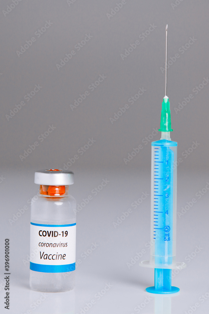 Corona virus vaccine bottle and syringe on white and grey background. Corona virus vaccine approval and global pandemic concept. Corona virus vaccine bottle and syringe on white and grey background. Corona virus vaccine approval and global pandemic concept.