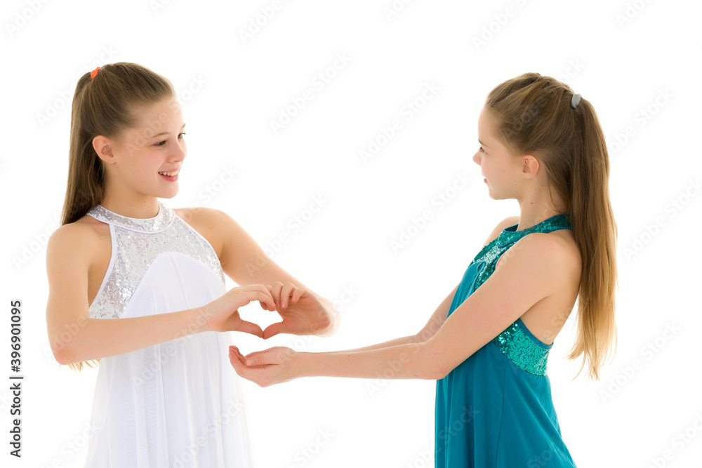 Two adorable girls gymnasts folded palms in the shape of a heart Two adorable girls gymnasts folded palms in the shape of a heart