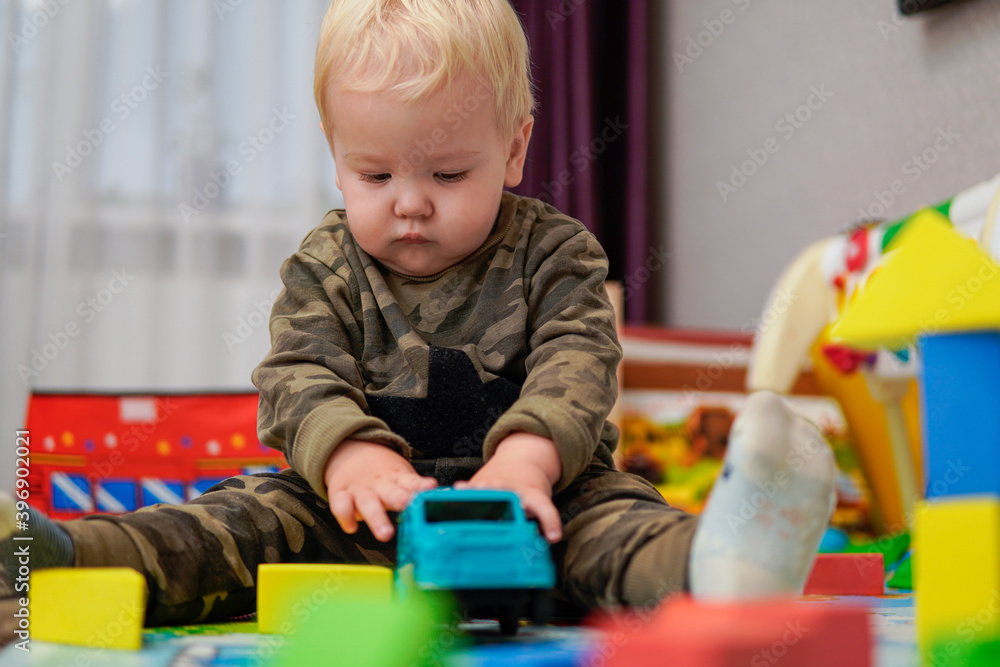 Little boy with blond hair playing with blue car Little boy with blond hair playing with blue car