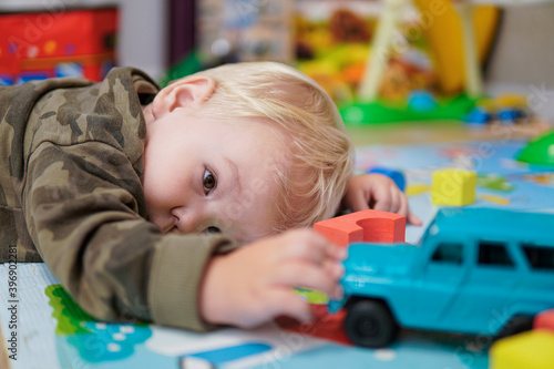 Little boy with blond hair playing with blue car