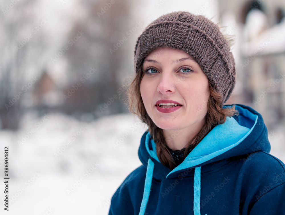 Portrait of a beautiful curly girl with a smile in a winter hat on a background of snow Portrait of a beautiful curly girl with a smile in a winter hat on a background of snow
