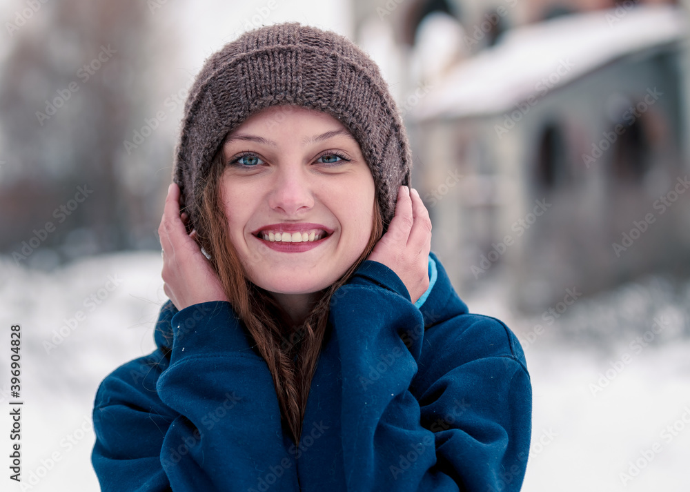 Portrait of a beautiful curly girl with a smile in a winter hat on a background of snow Portrait of a beautiful curly girl with a smile in a winter hat on a background of snow