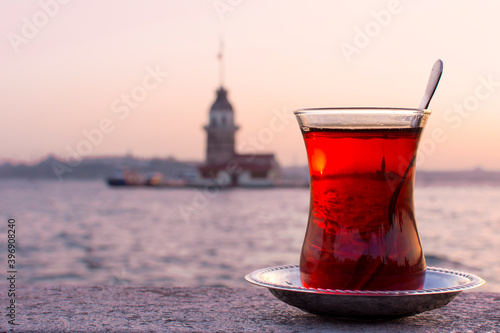 Magnific view of Maiden's Tower (aka Kiz kulesi) at night time on the background and traditional turkish tea on the front. Istanbul attractions.