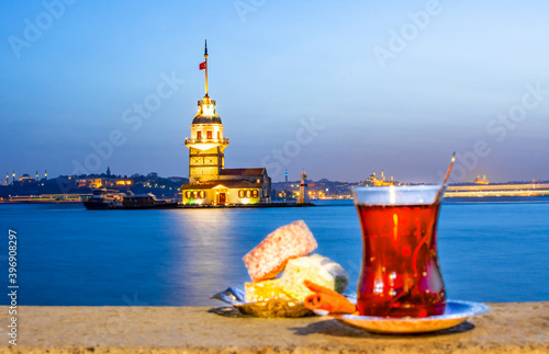 Canvastavla Magnific view of Maiden's Tower (aka Kiz kulesi) at night time on the background and traditional turkish tea with colorful turkish delight on the front