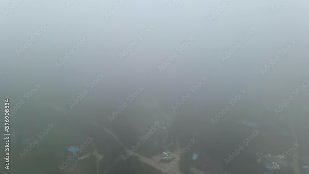 Aerial view through thick fog, overlooking a village, dark, foggy day, in the Carpathian Mountains, Ukraine - dolly, drone shot Aerial view through thick fog, overlooking a village, dark, foggy day, in the Carpathian Mountains, Ukraine - dolly, drone shot