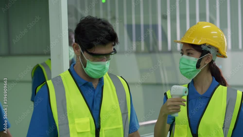 Multi ethnic group of production line workers check body temperature before working. Concept of new normal working lifestyle after Covid 19 pandemic, and diversity group of people. Multi ethnic group of production line workers check body temperature before working. Concept of new normal working lifestyle after Covid 19 pandemic, and diversity group of people.