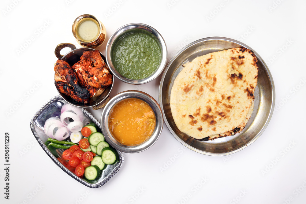 Spicy red Chicken grilled tikka tandoori nan bread green spinach curry yogurt sauce dal tomato cucumber onion salad set in metal stainless steel brass copper pot on white background Spicy red Chicken grilled tikka tandoori nan bread green spinach curry yogurt sauce dal tomato cucumber onion salad set in metal stainless steel brass copper pot on white background