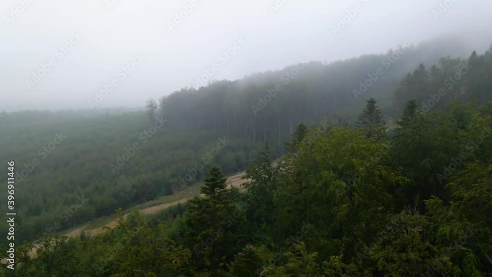Aerial view over foggy forest and a road, on a mysterious, moody day, in the Carphatian mountains, Ukraine - rising, drone shot Aerial view over foggy forest and a road, on a mysterious, moody day, in the Carphatian mountains, Ukraine - rising, drone shot
