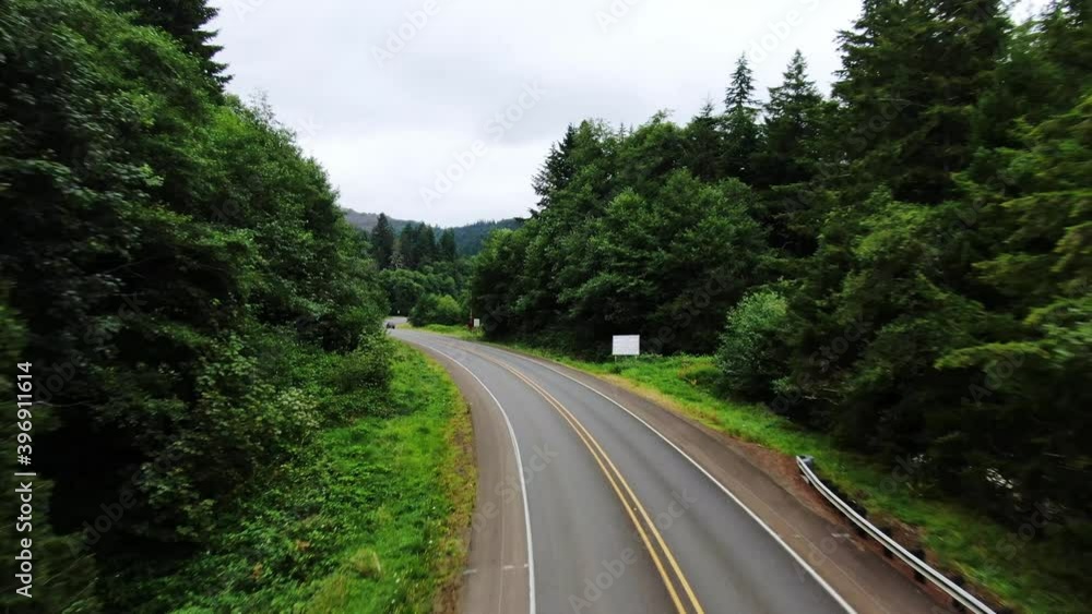 Aerial flight along highway road through beautiful lush green forest along coast Aerial flight along highway road through beautiful lush green forest along coast