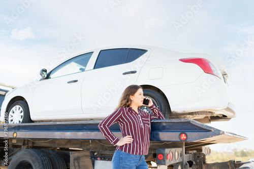 Profile of a woman on the phone and waiting for her ride next to a tow truck