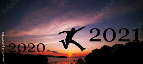 New year 2021 concept of Silhouette travel man jumping on the cliff in sunrise or sunset time to 2021 new year,image for happy new year background.