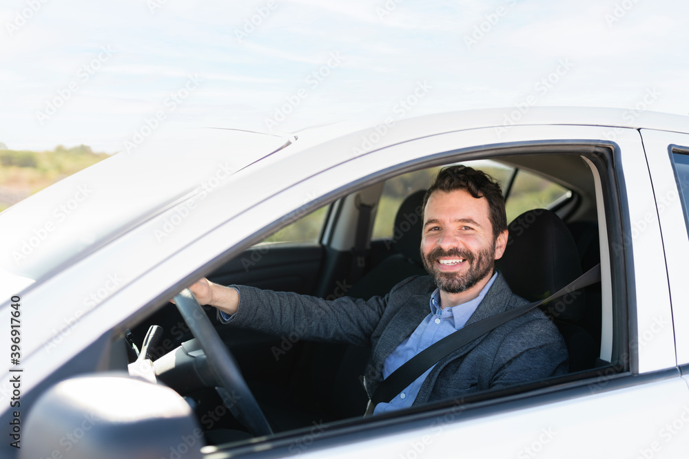 Good-looking male driver smiling and driving on the highway