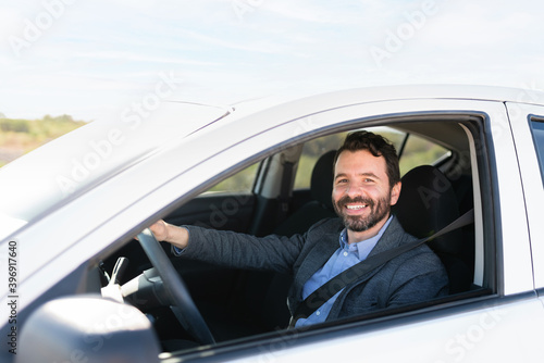 Good-looking male driver smiling and driving on the highway