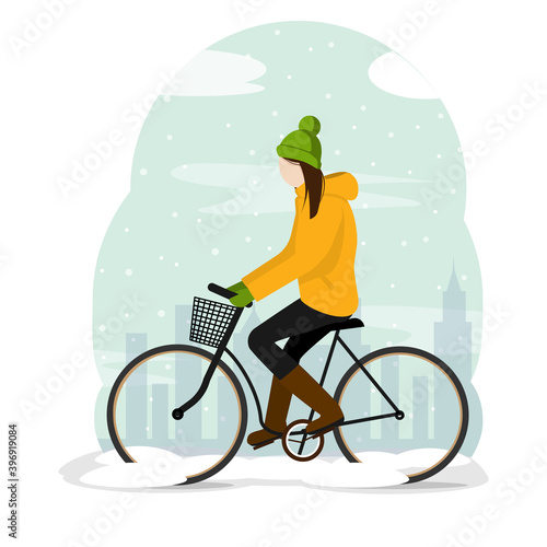 The girl walks on a bicycle in the winter city. It's snowing outside.