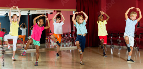 Happy little boys and beautiful girls having dancing class and hands up in class