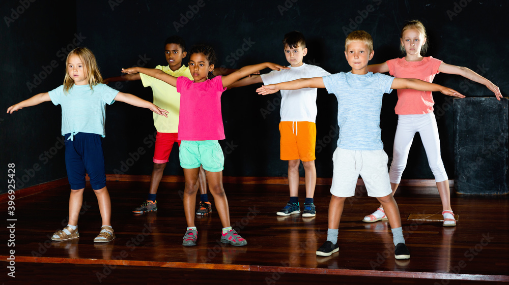 Fototapeta premium Group of cheerful positive little boys and beautiful girls having dancing class in studio in the evening