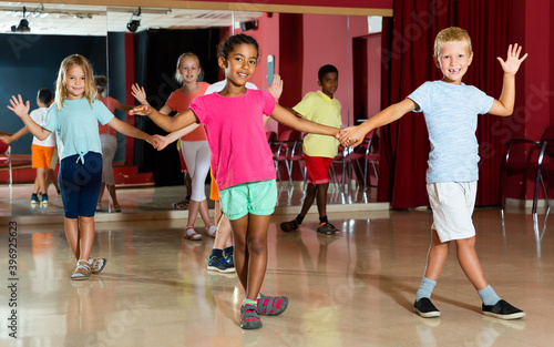 Friendly children trying dancing partner dance in modern studio