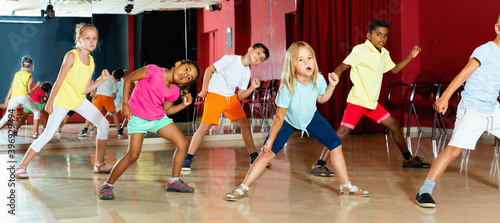 Fototapeta Naklejka Na Ścianę i Meble -  Positive smiling children studying modern style dance in class indoors