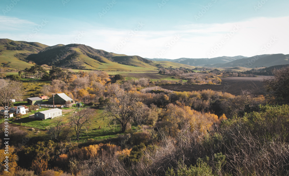 A rural farm with a barn and home and a field in the hills of central California on a sunny day in autumn A rural farm with a barn and home and a field in the hills of central California on a sunny day in autumn