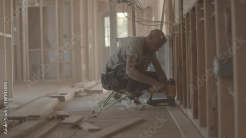 Man is nailing down hardwood flooring at a house