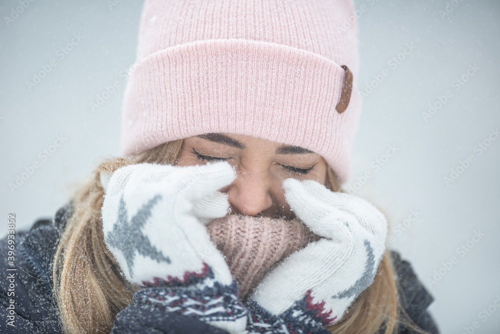 Female closing here eyes and warming up her hands on a very cold day Female closing here eyes and warming up her hands on a very cold day