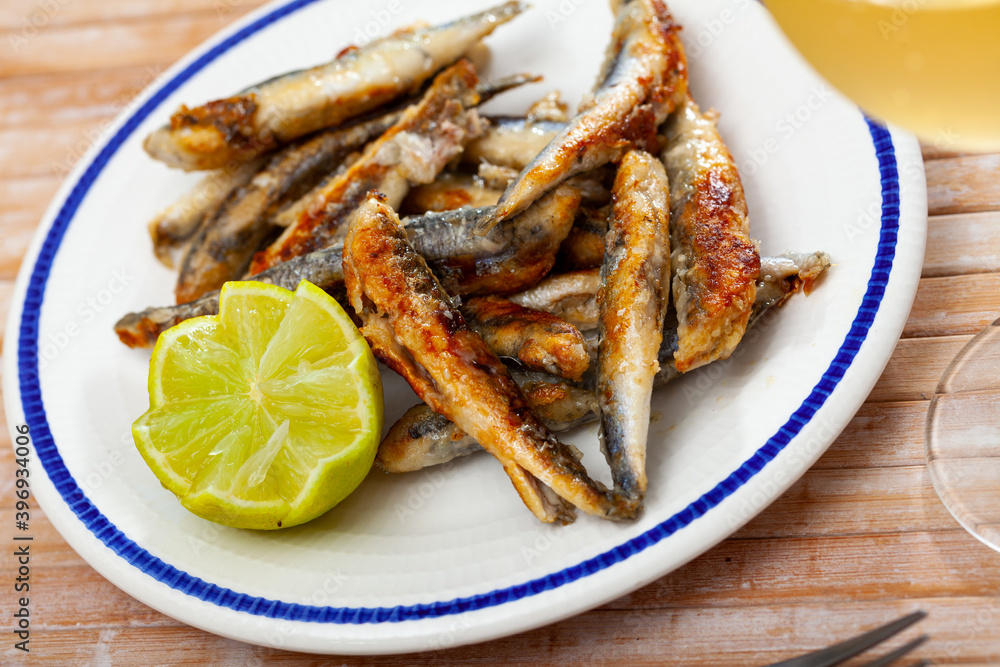 Fried anchovies with lemon on a plate closeup
