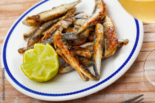 Fried anchovies with lemon on a plate closeup