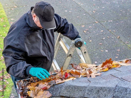 Man cleaning leaves from roof gutter 