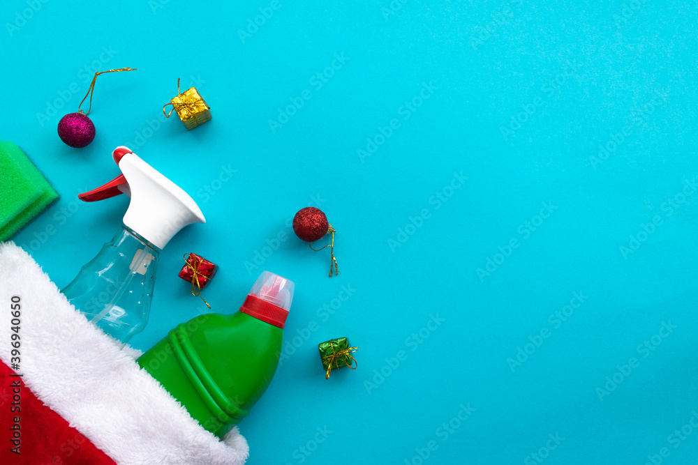 Santa hat with gifts for Christmas greeting. House cleaning supplies on blue background. Cleaning business, production, shopping and delivery. copy space on top.