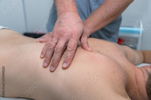 Masseur gives therapeutic massage to man. Male hands do massage of back to patient man. Male patient having massage in clinic. Man relaxing on massage table