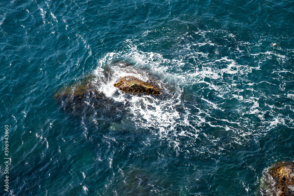 Waves crash against the rocks. Top view of the sea