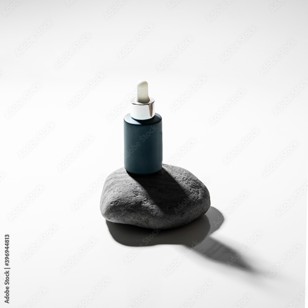 Blue bottle with natural facial cream on stone podium on white background. Modern concept for Natural skin care. Blue bottle with natural facial cream on stone podium on white background. Modern concept for Natural skin care.