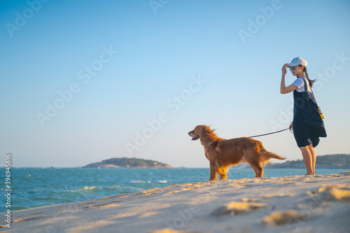 Golden Retriever and girl walking on the beach