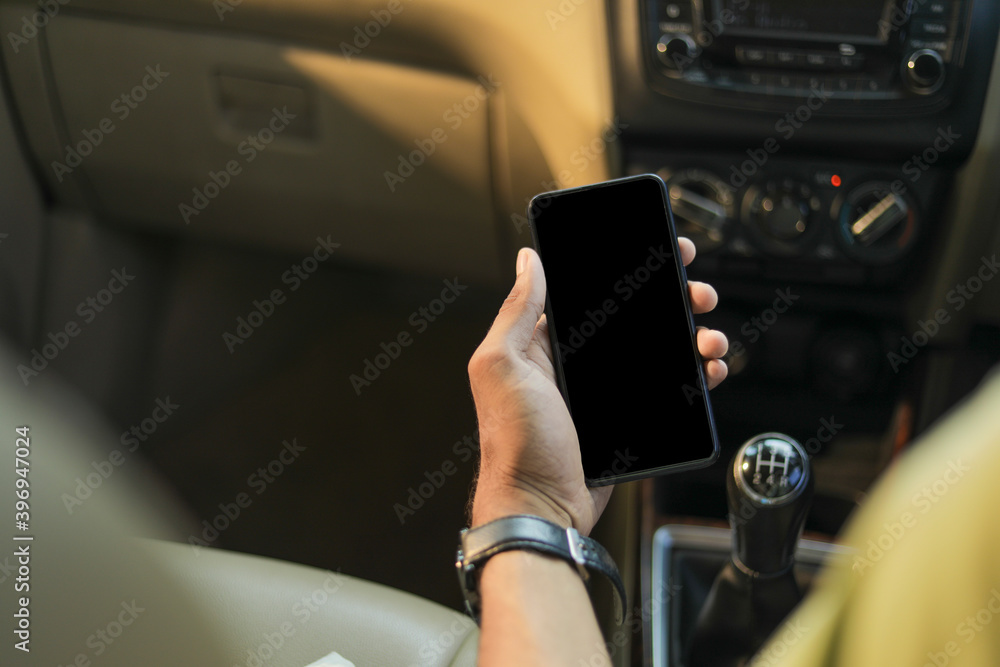 male hand holding mobile phone in car