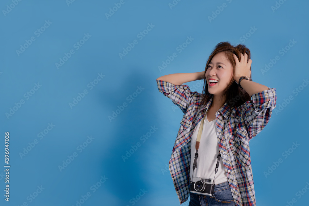 Young Asian tourists are amazed in summer clothes with a camera and looking to the side on blue studio background.