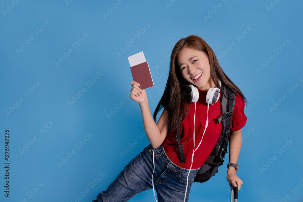 Young Asian tourists are excited to travel. She is holding a passport on a blue background in the studio. Young Asian tourists are excited to travel. She is holding a passport on a blue background in the studio.