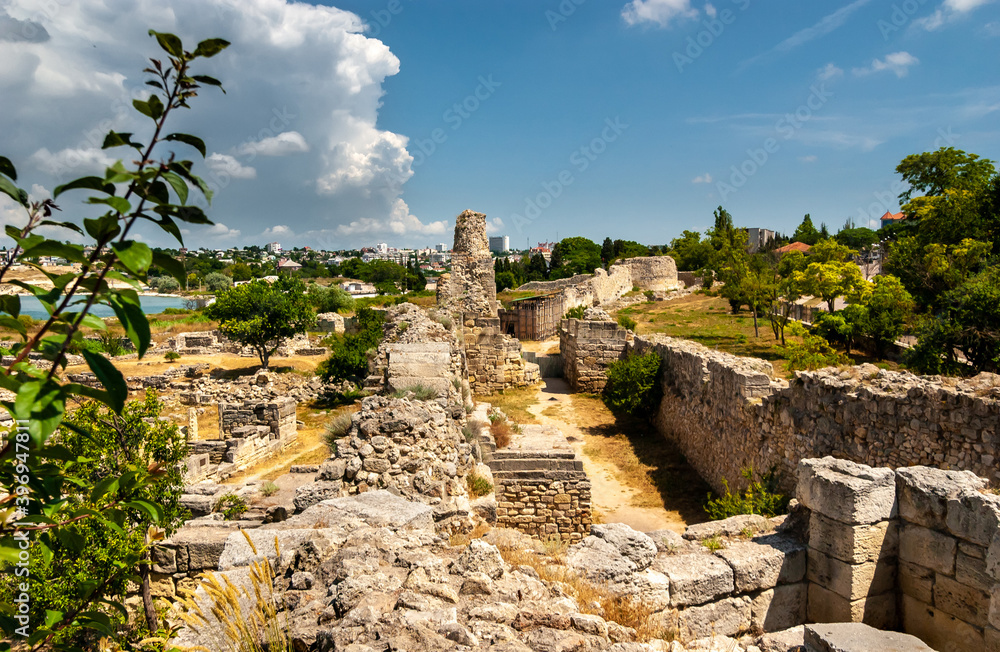 Remains of ancient antique fortress walls, the outer one is low and the inner one is high. In the distance the sea bay. Excavations of the ancient city of Chersonesos. Sevastopol city, Crimea.